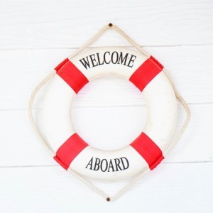 White Life buoy with welcome aboard on white wall.